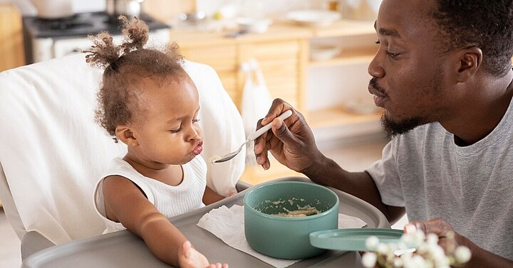 Dad feeding daughter