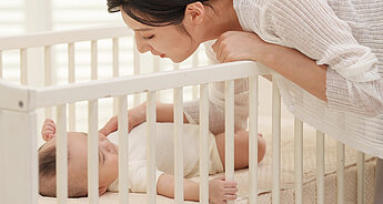 Mum putting sleeping baby in crib