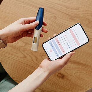 Woman holding ovulation test and cycle tracker